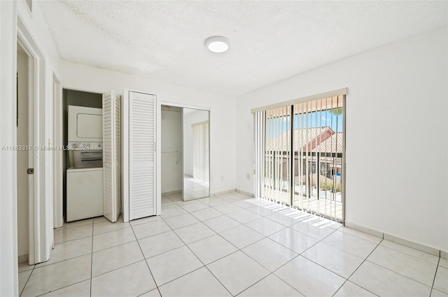 unfurnished bedroom featuring stacked washer and clothes dryer, a textured ceiling, access to outside, and light tile patterned floors