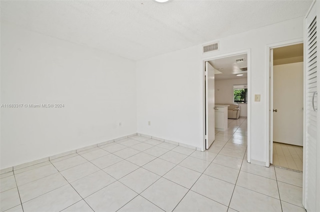 spare room featuring a textured ceiling and light tile patterned floors