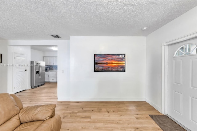 living room with a textured ceiling and light hardwood / wood-style flooring