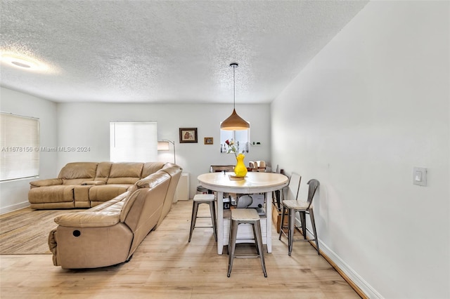 dining space featuring a wealth of natural light, light hardwood / wood-style flooring, and a textured ceiling