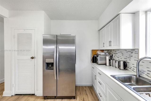 kitchen featuring sink, white cabinetry, stainless steel refrigerator with ice dispenser, and light hardwood / wood-style flooring