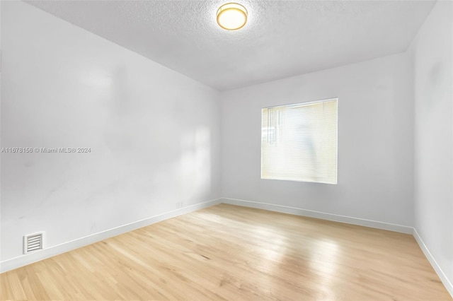 spare room featuring light hardwood / wood-style floors and a textured ceiling