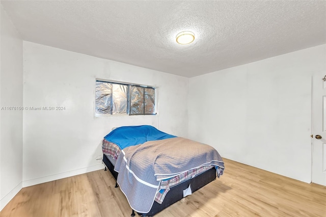 bedroom with a textured ceiling and hardwood / wood-style flooring