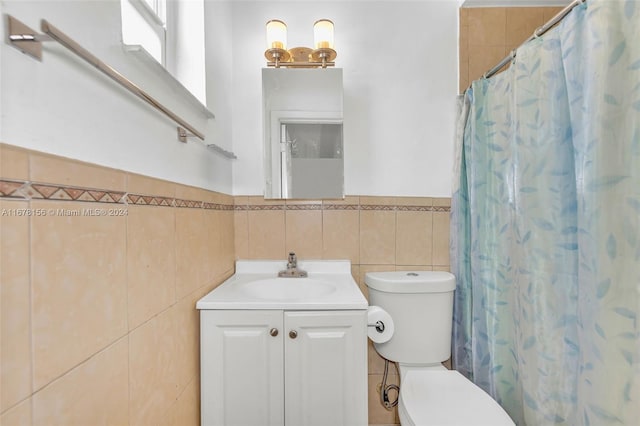 bathroom featuring vanity, toilet, and tile walls