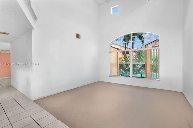 tiled spare room with a high ceiling