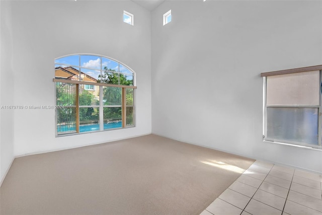 carpeted spare room with a high ceiling