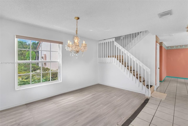 interior space featuring light hardwood / wood-style floors, a notable chandelier, and a textured ceiling