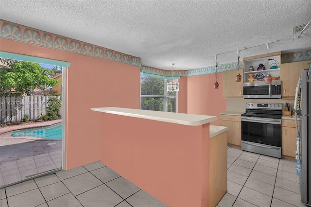 kitchen featuring kitchen peninsula, a textured ceiling, and stainless steel appliances