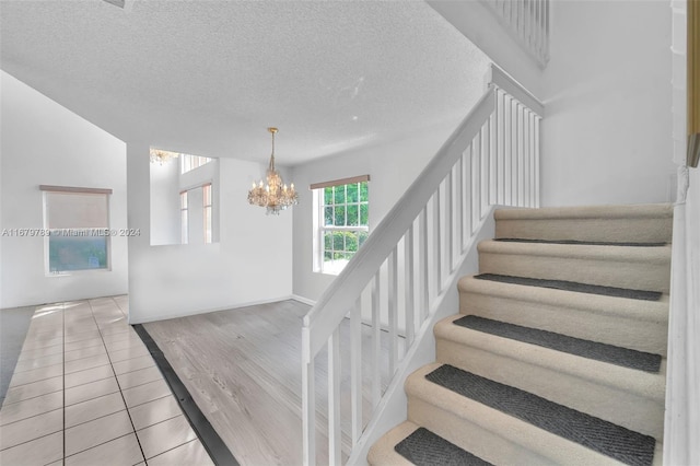 stairs featuring a textured ceiling, a chandelier, and tile patterned floors