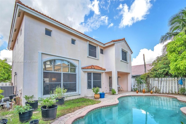 rear view of property featuring central air condition unit, a patio area, and a fenced in pool