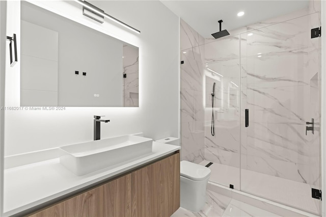 bathroom featuring a shower with door, vanity, and toilet