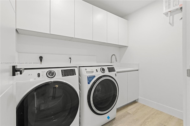 laundry room with light hardwood / wood-style floors, cabinets, and washer and clothes dryer