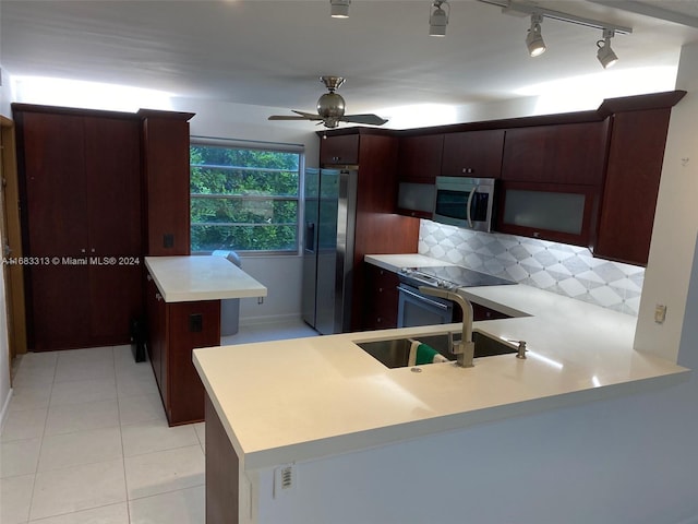 kitchen with stainless steel appliances, kitchen peninsula, tasteful backsplash, ceiling fan, and light tile patterned floors