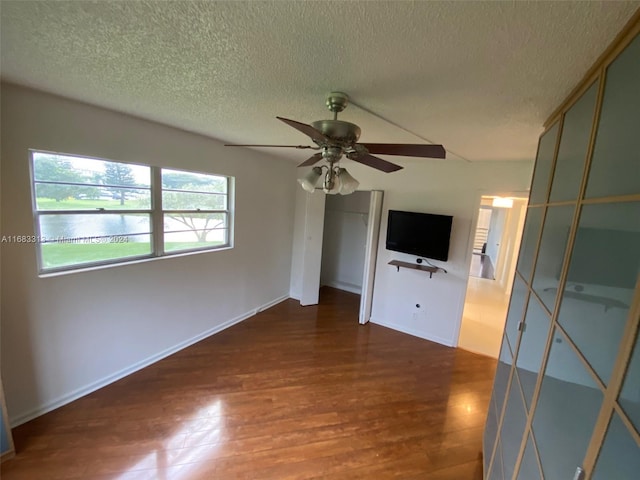 unfurnished living room with dark wood-type flooring, a textured ceiling, and ceiling fan