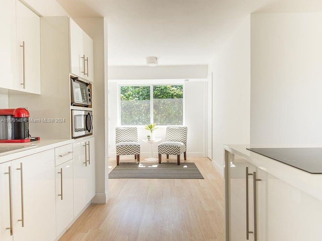 11515 NE 12th Ave, Miami, FL 33161 - kitchen with stainless steel microwave, light wood finished floors, white cabinets, and light countertops
