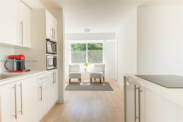 11515 NE 12th Ave, Miami, FL 33161 - kitchen featuring stainless steel microwave, light wood-style floors, white cabinets, and light countertops