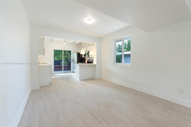 unfurnished room with light hardwood / wood-style flooring, sink, and track lighting