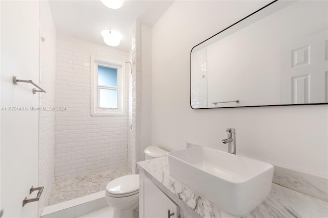 bathroom featuring vanity, toilet, and tiled shower