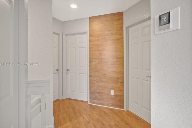 hall featuring light hardwood / wood-style floors and wood walls