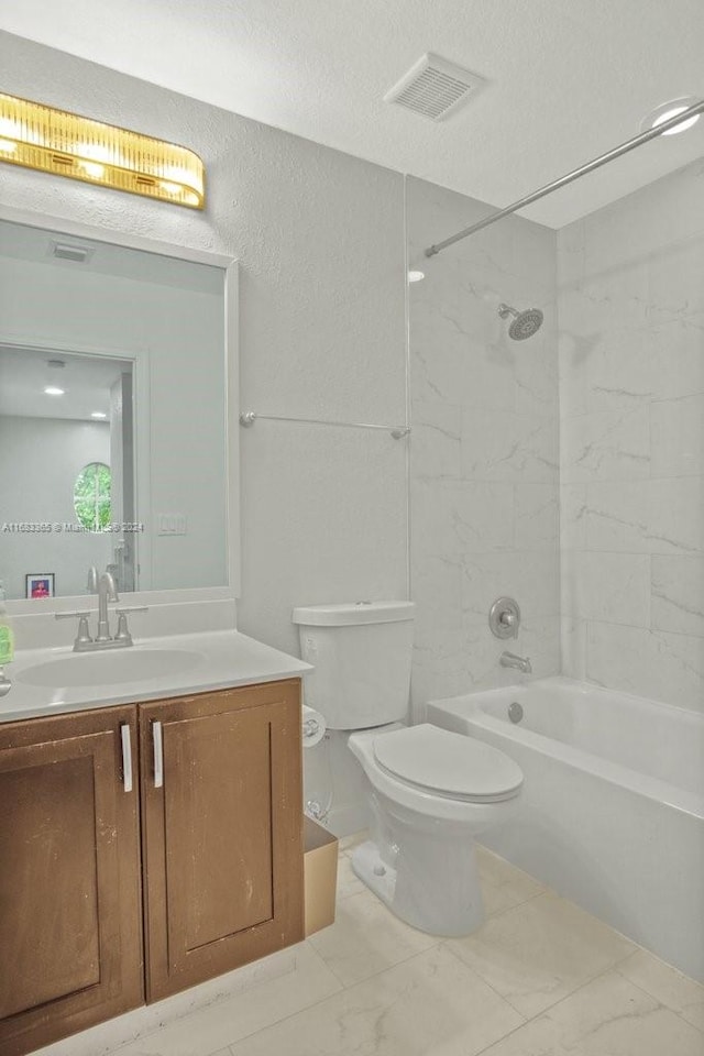 full bathroom with tiled shower / bath, vanity, a textured ceiling, and toilet