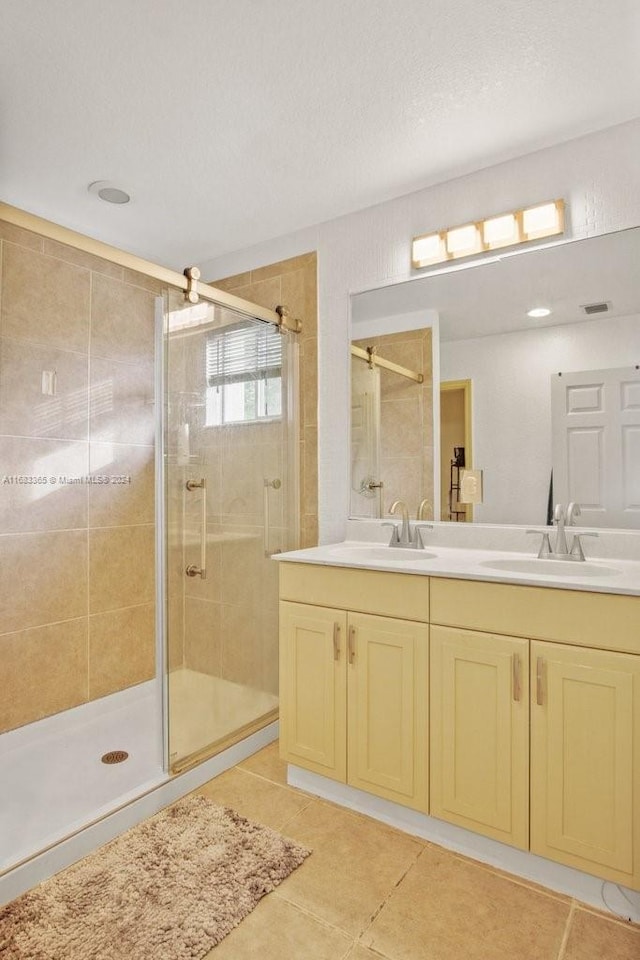 bathroom with vanity, a textured ceiling, a shower with shower door, and tile patterned flooring