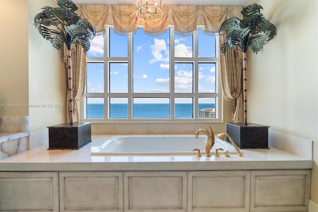 bathroom with a tub to relax in, a wealth of natural light, and a water view