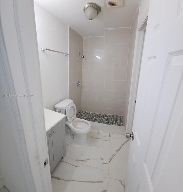 bathroom featuring vanity, toilet, and tiled shower