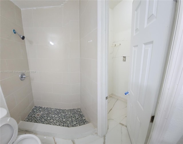 bathroom featuring a tile shower and toilet