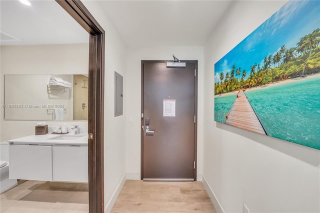 doorway to outside with light hardwood / wood-style floors, electric panel, and sink