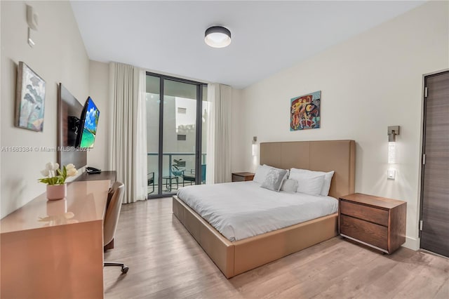 bedroom featuring access to exterior, light wood-type flooring, and floor to ceiling windows