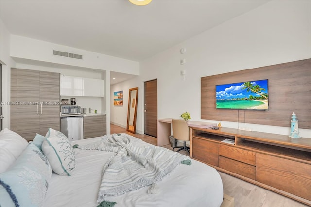 bedroom with stainless steel fridge and light wood-type flooring