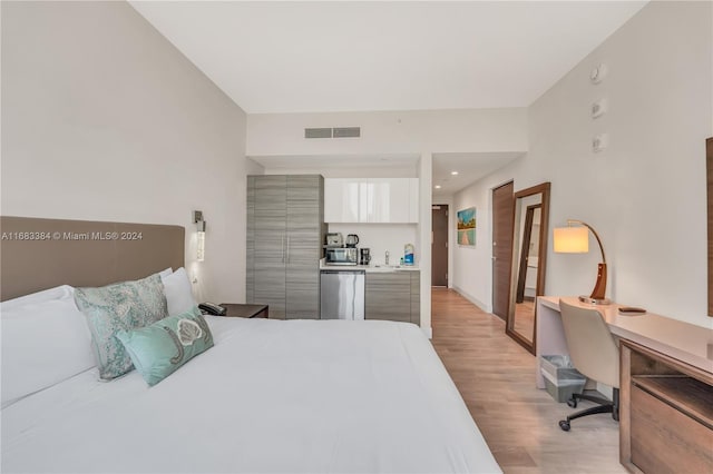 bedroom featuring sink, stainless steel fridge, and light wood-type flooring