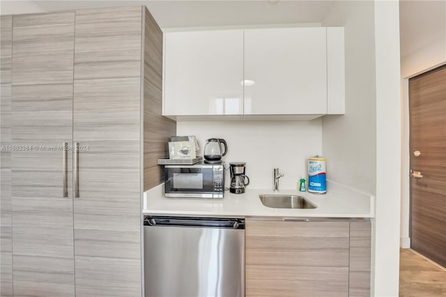 kitchen featuring white cabinets, stainless steel appliances, sink, and light wood-type flooring