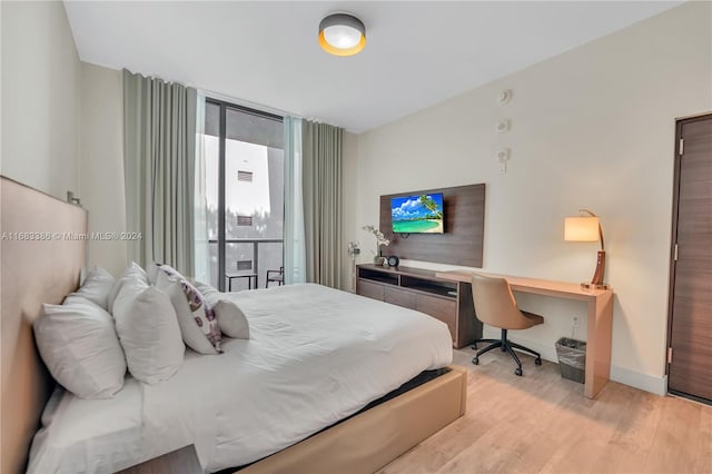 bedroom featuring built in desk, light wood-type flooring, and floor to ceiling windows