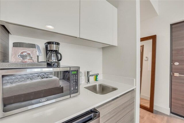777 N Ocean Dr Unit S316, Hollywood, FL 33019 - kitchen with stainless steel microwave, modern cabinets, light countertops, light wood-style flooring, and white cabinetry