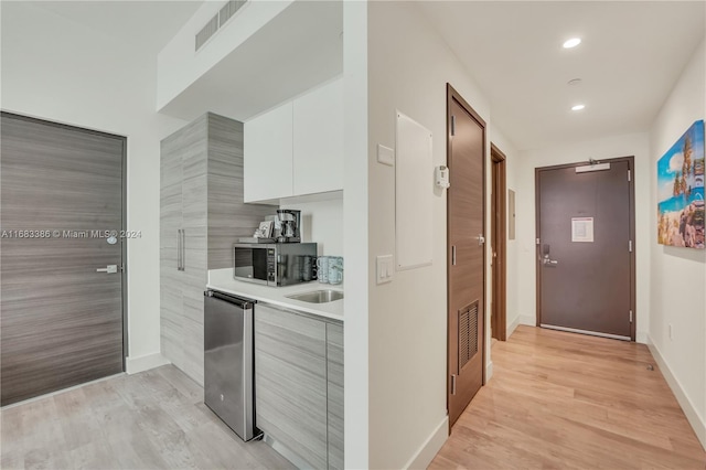 kitchen with appliances with stainless steel finishes, white cabinetry, and light wood-type flooring