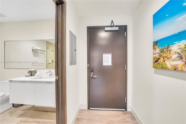 doorway featuring electric panel, sink, and light wood-type flooring