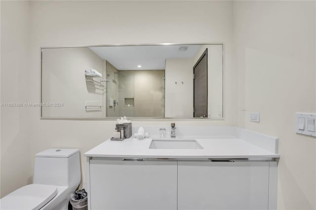 bathroom with toilet, vanity, and a shower with door