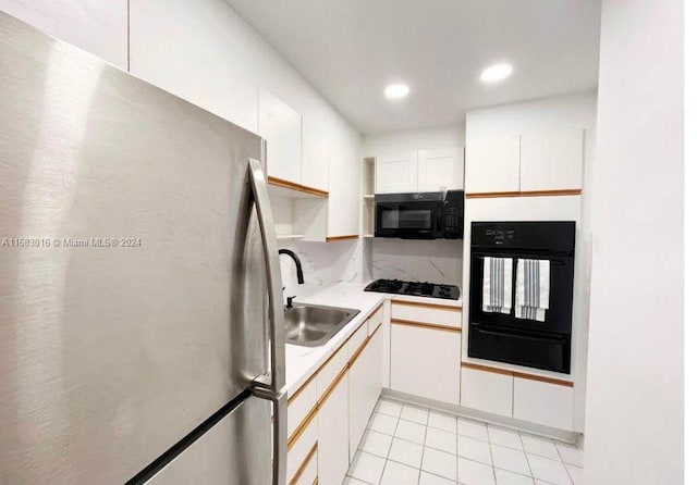 kitchen featuring white cabinets, black appliances, sink, and light tile patterned floors