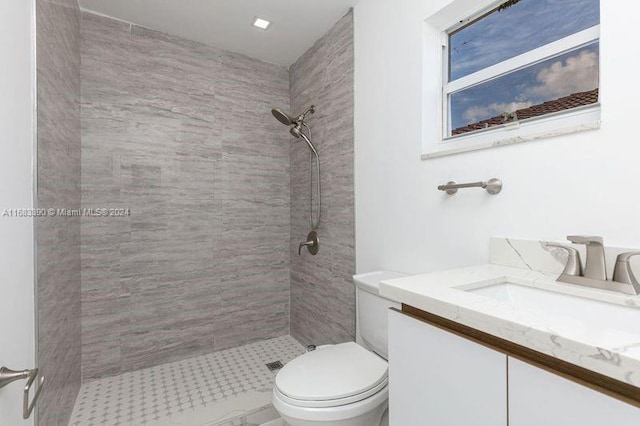 bathroom with vanity, a tile shower, and toilet