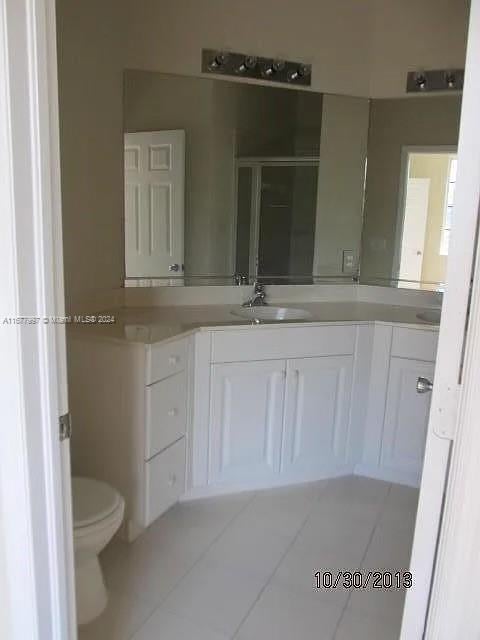 bathroom featuring vanity, a shower with shower door, toilet, and tile patterned floors