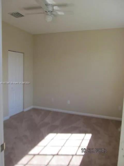 carpeted spare room with ceiling fan