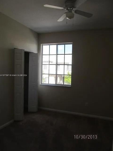 unfurnished bedroom with dark carpet and ceiling fan