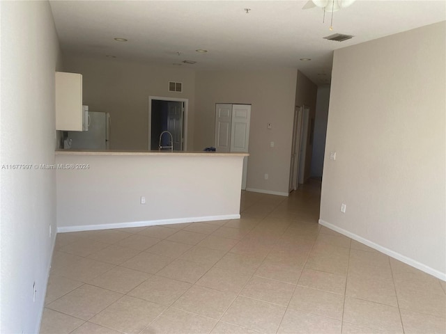 empty room with ceiling fan and light tile patterned floors