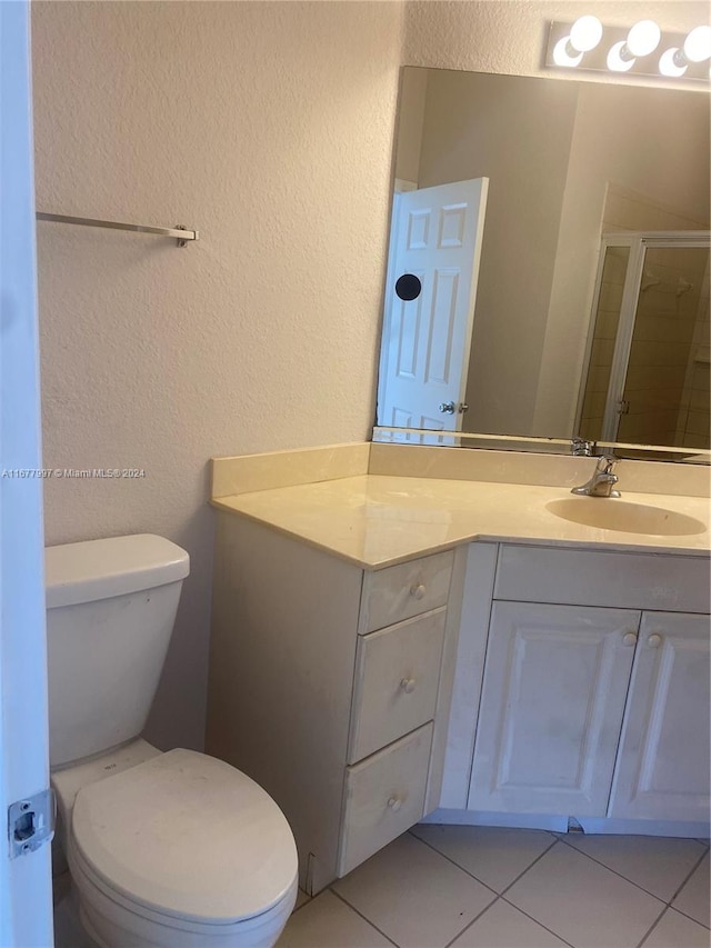 bathroom with toilet, walk in shower, vanity, and tile patterned flooring