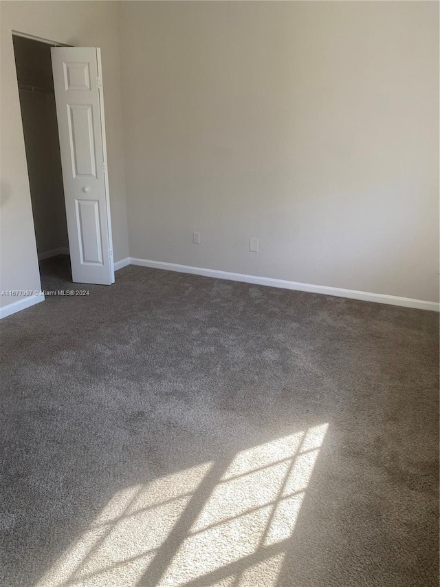 spare room with dark carpet