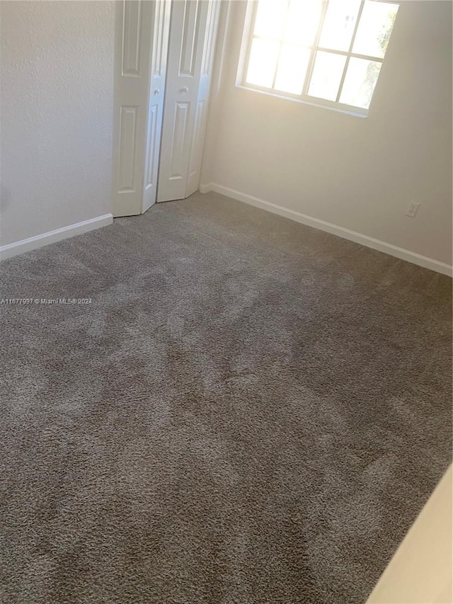 unfurnished room with dark colored carpet