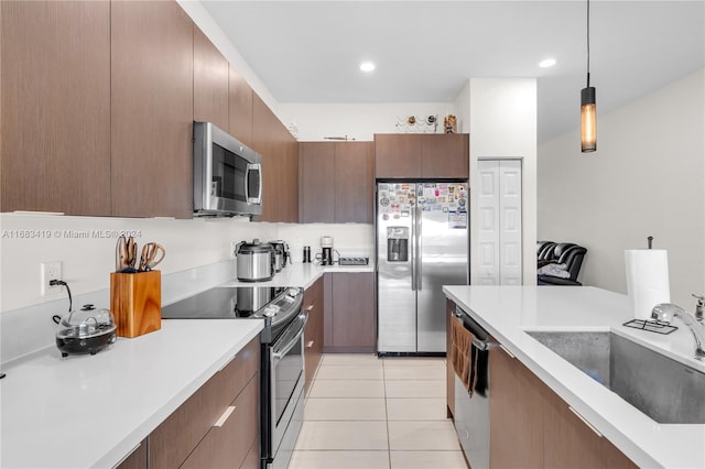 kitchen featuring decorative light fixtures, light tile patterned floors, sink, and appliances with stainless steel finishes