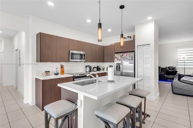 kitchen featuring sink, light tile patterned flooring, stainless steel appliances, and decorative light fixtures