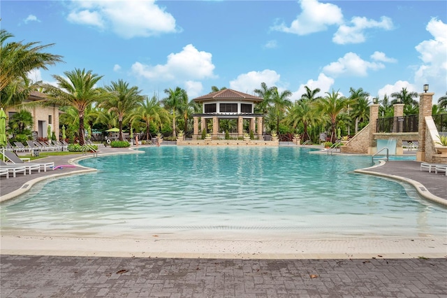 view of swimming pool with a patio area and a beach view